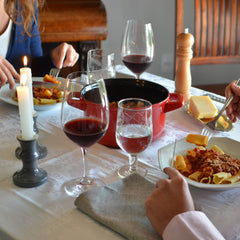 Dining table with pasta, wine glasses, and candles in a cozy setting.